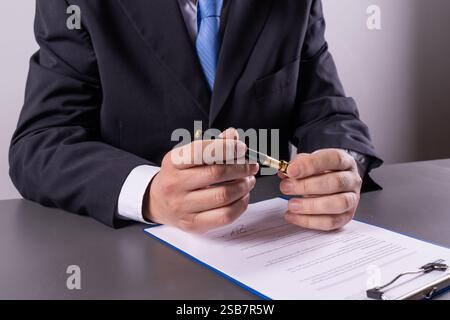 Dirigeant d'entreprise enlevant le capuchon du stylo tout en se préparant à signer un document important au bureau, en se concentrant sur la précision et le professionnalisme. Banque D'Images