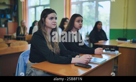 Les élèves du secondaire se sont activement engagés dans une leçon en classe, écoutant attentivement leur professeur Banque D'Images