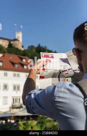 Jeune homme, voyageur de vacances en ville regardant la carte touristique tout en visitant et en explorant les attractions. Concept de modes de vie itinérants. Banque D'Images