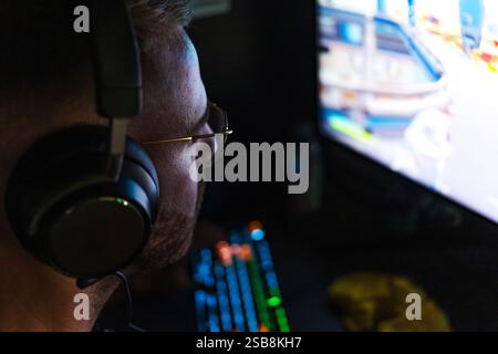 Joueur homme participant à une compétition de jeu, assis devant un écran d'ordinateur et jouant à des jeux vidéo. Banque D'Images
