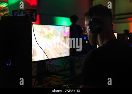 Joueur homme participant à une compétition de jeu, assis devant un écran d'ordinateur et jouant à des jeux vidéo. Banque D'Images