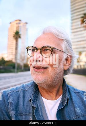 Homme senior élégant marchant dans la ville au crépuscule, appréciant la retraite Banque D'Images