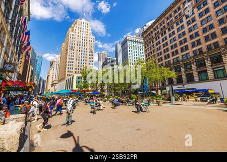 Les gens se relaxent sur des chaises dans le public Herald Square entouré d'arbres et de bâtiments historiques le jour ensoleillé. New York. ÉTATS-UNIS. Banque D'Images