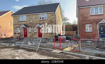 Maisons en briques nouvellement construites en cours de développement, montrant l'aménagement paysager inachevé, des clôtures temporaires et des matériaux de construction. Une maison dispose de R Banque D'Images