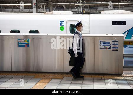 OSAKA, JAPON : un train à grande vitesse Shinkansen N700 à la gare de Shin-Osaka avec un personnel de gare sur le quai. Banque D'Images