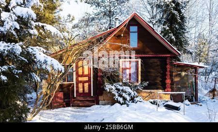 vue panoramique de la maison en rondins de campagne sur cour enneigée dans le village le jour d'hiver Banque D'Images