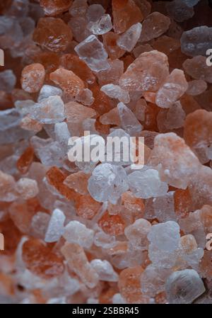 Vue rapprochée du sel rose de l'Himalaya sur la surface texturée de couleurs vives. Cristaux et blocs écrasés de sel rose naturel en arrière-plan, Chipped Hi Banque D'Images