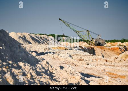 La pelle de marche fonctionne près des rangées de pieux dans la fosse minière Banque D'Images