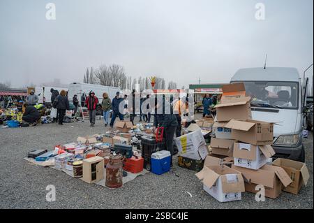 Hunedoara, Roumanie - 25 janvier 2025 : foule de gens et divers objets, jouets, outils et appareils électroniques à un marché aux puces. Banque D'Images