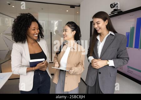 Groupe diversifié de trois jeunes collègues joyeux parlant et riant Banque D'Images