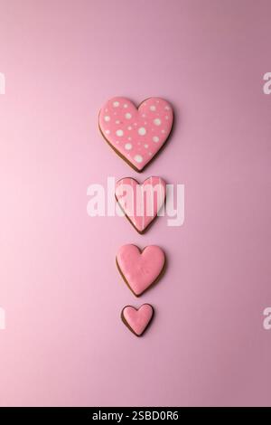 Biscuits en pain d'épices en forme de coeurs avec glaçage rose, concept de cuisson créative minimaliste pour la Saint-Valentin Banque D'Images