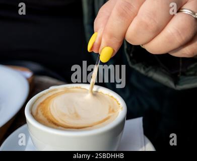 Une personne remuant un cappuccino avec une cuillère, gros plan sur la mousse Banque D'Images