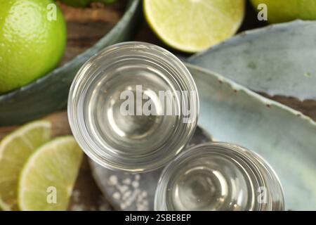 Coups de tequila avec du sel, des citrons verts et des feuilles d'agave sur la table, pose à plat Banque D'Images