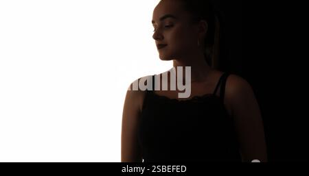 Confiance féminine. Silhouette de beauté. Contour sombre du visage pensif de femme tranquille isolé sur fond d'espace vide blanc. Banque D'Images