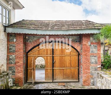 L'entrée en bois de la mosquée Imam Ali à Shaki, en Azerbaïdjan, comprend une porte cintrée en bois flanquée de murs de pierre et ornée de verdure Banque D'Images