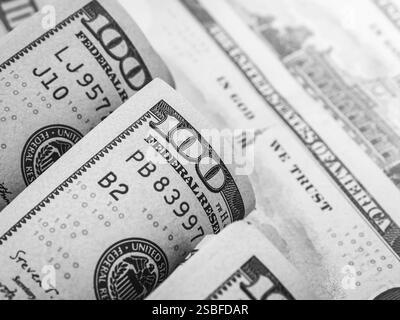 Fermez les numéros 100 sur les billets de banque de billets de dollars. Argent comptant, arrière-plan financier. Cent billets de banque de dollars roulent arrière-plans, style noir et blanc. Banque D'Images