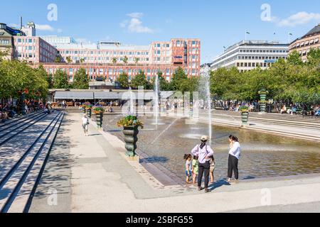 Les gens apprécient la fontaine de Wolodarski et l'ombre des cerisiers dans le Kungsträdgården (jardin du Roi) à Stockholm, en Suède, par une journée ensoleillée. Banque D'Images