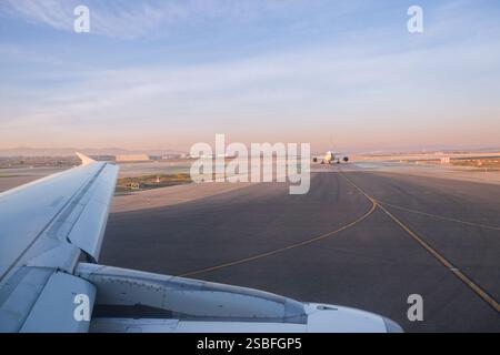Vue de l'intérieur d'un avion entrant dans la piste de décollage. Il y a un avion plus tard sur le point de décoller au coucher du soleil. Aventure, début, Banque D'Images