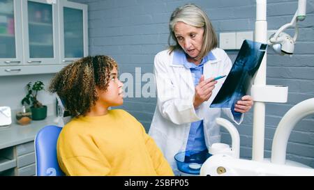Dentiste expliquant les résultats d'une radiographie à un patient en cabinet dentaire Banque D'Images