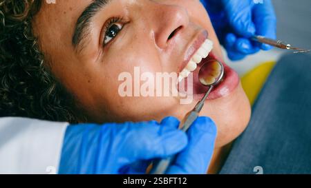 Patient subissant un examen dentaire avec le dentiste utilisant des outils médicaux et des mains gantées Banque D'Images