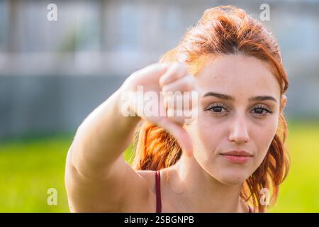 Gros plan jeune femme montrant Thumbs Down Gesture à l'extérieur Banque D'Images