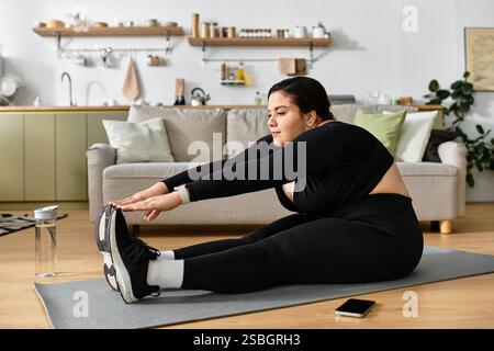 Une jeune femme de grande taille aime s'étirer sur un tapis dans son espace de vie chaleureux et accueillant. Banque D'Images