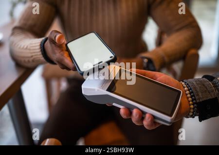 Gros plan de l'homme fait un paiement sans contact avec smartphone dans le bar. Banque D'Images