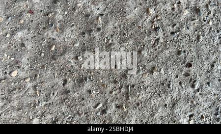 Vue rapprochée d'une surface en béton montrant sa texture rugueuse et ses pierres encastrées. Banque D'Images