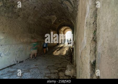Touristes dans le tunnel d'entrée de l'amphithéâtre de Pompéi dans les ruines romaines antiques de Pompéi en Italie. Banque D'Images