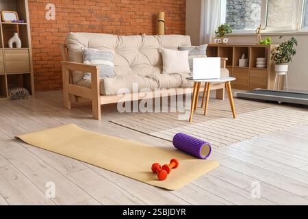Tapis de fitness avec haltères et rouleau en mousse à l'intérieur du salon Banque D'Images