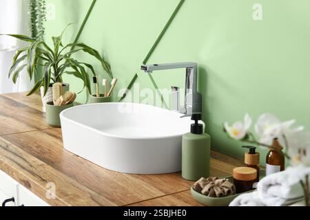 Commode avec lavabo, fournitures de bain près du mur vert dans la salle de bains Banque D'Images