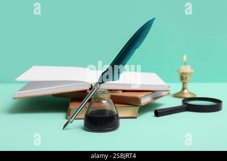 Livres avec plume, encrier et loupe sur fond vert Banque D'Images
