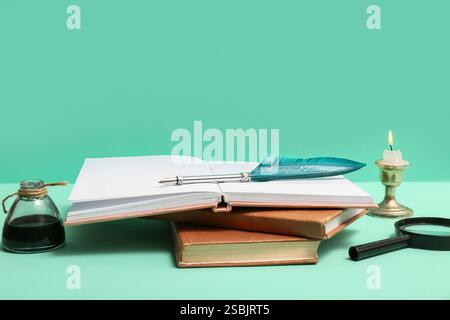 Livres avec plume, encrier et loupe sur fond vert Banque D'Images
