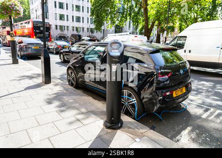 Voiture électrique branchée à un point de recharge de véhicule électrique dans la rue, Mayfair, Londres, Angleterre Banque D'Images