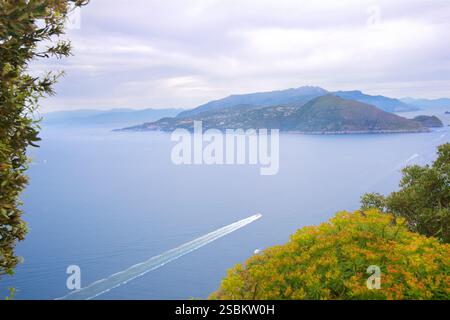 Petit bateau dans la mer Tyrrhénienne au large de la côte de l'île de Capri. Vue sur la baie de Naples depuis l'île de Capri vers l'île d'Ischia. Banque D'Images