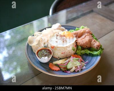 Riz frit servi avec poulet frit, oeuf, sauce piment, laitue, carottes tranchées, concombre et etc Banque D'Images