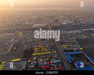 Une vue aérienne époustouflante de Mahakumbh tente ville au coucher du soleil, baignée de teintes dorées. Les vastes tentes brillent sous le ciel du soir, créant une vue sereine Banque D'Images