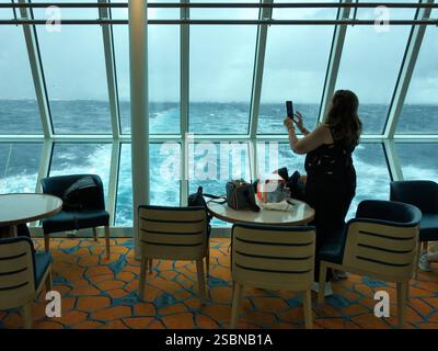 Femme prenant photo avec téléphone du bar-salon panoramique du ferry 'Dalmacija' de Bari à Dubrovnik Banque D'Images