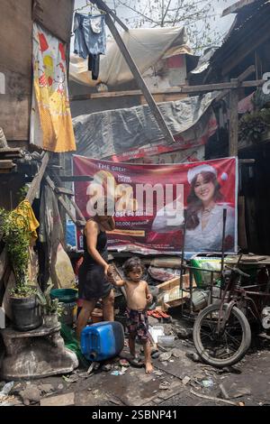 Philippines, Manille, Malabon, femme et son enfant en fornt de leur logement de fortune dans un bidonville Banque D'Images