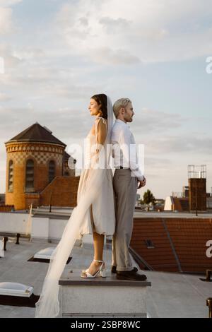 Vue latérale du jeune pont et du marié debout dos à dos sur le toit Banque D'Images