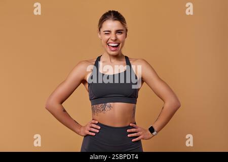 Une jeune femme confiante et énergique pose joyeusement dans des vêtements de sport élégants, mettant efficacement en valeur sa forme physique impressionnante et son énergie vibrante, toutes les s. Banque D'Images