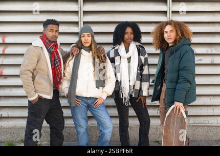 Quatre jeunes amis à la mode posent ensemble dans une rue de la ville, mettant en valeur leurs tenues hivernales à la mode et leurs styles divers Banque D'Images