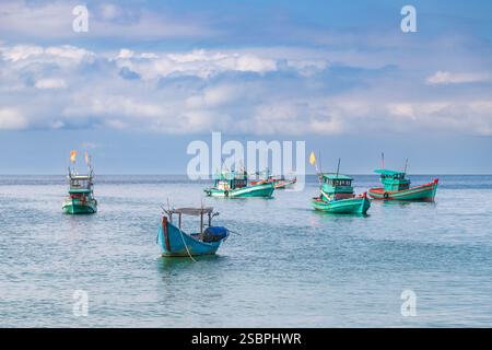Scène côtière sereine avec plusieurs bateaux de pêche traditionnels flottant sur des eaux calmes et turquoises. Banque D'Images