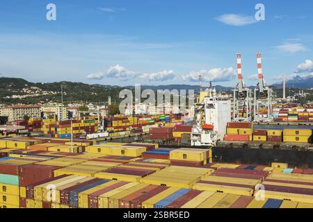 Vue en angle élevé de conteneurs d'expédition de boîtes métalliques rectangulaires empilés sur le quai en attente d'être chargés sur le navire de charge MSC Renaissance III à la Spezia c Banque D'Images