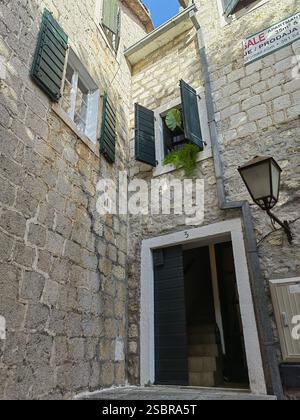 Entrée d'une maison en pierre dans la vieille ville de Budva avec des fenêtres blanches et des volets verts Banque D'Images