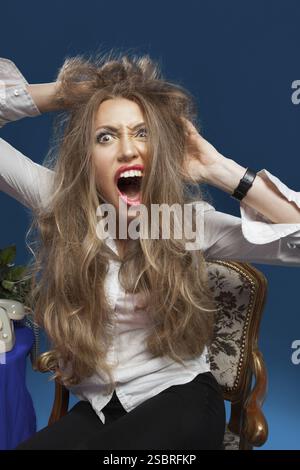 Femme blonde en colère avec les cheveux déséchevelés criant Banque D'Images