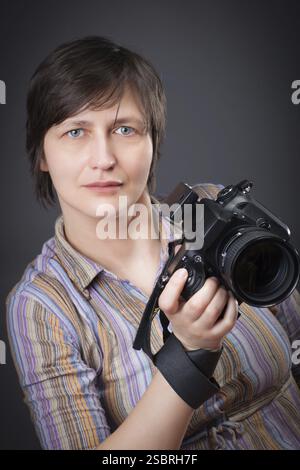 Femme photographe avec appareil photo ower gris bavground Banque D'Images