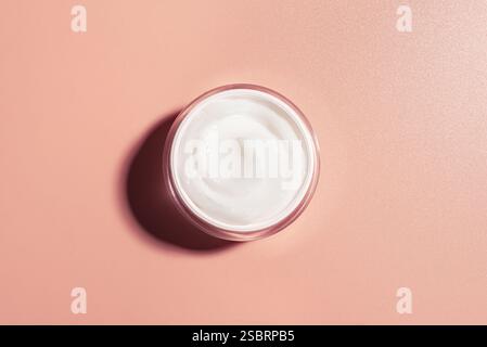 Pot de crème cosmétique ouvert sur fond beige rose, vue de dessus, espace de copie. Produit de beauté gel rétinol pour soins anti agining visage, routine quotidienne. Ouvert Banque D'Images