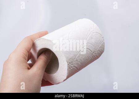 Une main féminine prend un rouleau de papier toilette blanc à la main Banque D'Images