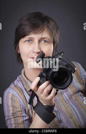 Femme photographe avec appareil photo ower gris bavground Banque D'Images